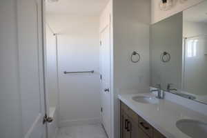 Bathroom featuring marble finish floor, double vanity, and a sink