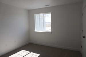 Carpeted spare room with visible vents and baseboards