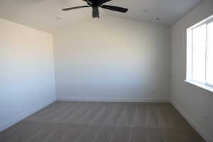 Carpeted empty room featuring vaulted ceiling, ceiling fan, visible vents, and baseboards