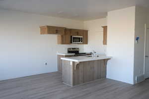 Kitchen featuring visible vents, appliances with stainless steel finishes, a sink, a peninsula, and baseboards