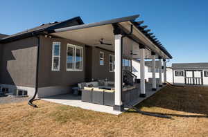 View of property exterior with a ceiling fan, a patio area, a yard, and outdoor lounge area