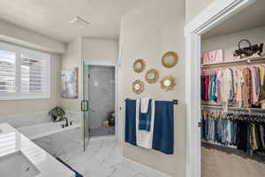 Full bathroom with a walk in closet, marble finish floor, a marble finish shower, visible vents, and a bath