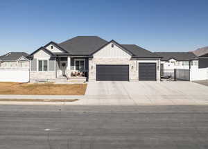 Modern farmhouse style home with stone siding, a gate, fence, and board and batten siding