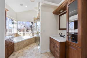 Full bath with a stall shower, lofted ceiling, stone tile flooring, vanity, and a bath