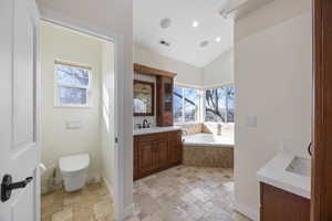 Bathroom with visible vents, vanity, stone tile flooring, and a healthy amount of sunlight