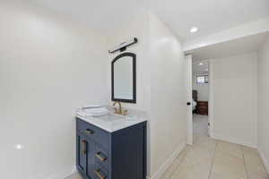 Bathroom featuring baseboards, recessed lighting, vanity, and tile patterned floors