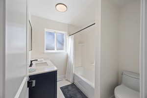 Full bathroom featuring shower / tub combo with curtain, double vanity, toilet, a sink, and baseboards