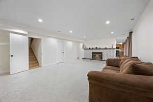 Living area featuring a fireplace, recessed lighting, light colored carpet, stairway, and baseboards