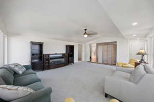 Carpeted living room featuring vaulted ceiling, a ceiling fan, and recessed lighting