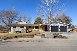 Ranch-style home with concrete driveway, a chimney, an attached garage, fence, and brick siding