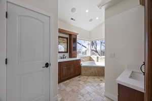 Full bathroom featuring lofted ceiling, a sink, two vanities, visible vents, and stone tile flooring