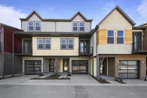 Townhome / multi-family property featuring a garage, concrete driveway, brick siding, and board and batten siding