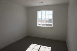 Unfurnished room with dark colored carpet, visible vents, and baseboards