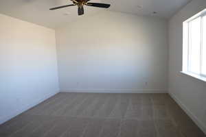 Carpeted spare room with vaulted ceiling, visible vents, ceiling fan, and baseboards