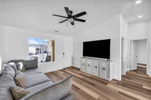 Living area with lofted ceiling, recessed lighting, ceiling fan, wood finished floors, and baseboards