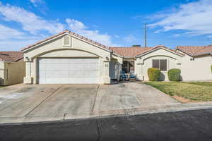 Mediterranean / spanish-style home featuring an attached garage, a tiled roof, concrete driveway, and stucco siding