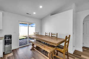 Dining room featuring arched walkways, recessed lighting, wood finished floors, visible vents, and baseboards