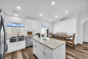 Kitchen with dark wood-type flooring, a kitchen island, a sink, visible vents, and appliances with stainless steel finishes