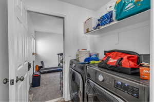 Clothes washing area featuring carpet, laundry area, and washing machine and clothes dryer