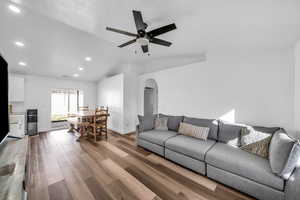 Living area featuring arched walkways, a ceiling fan, lofted ceiling, wood finished floors, and recessed lighting