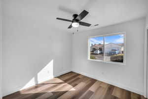 Unfurnished room featuring a ceiling fan, baseboards, visible vents, and wood finished floors