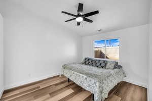 Bedroom featuring a ceiling fan, baseboards, visible vents, and wood finished floors