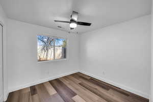 Empty room featuring ceiling fan, dark wood-style flooring, visible vents, and baseboards