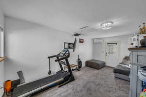 Exercise area featuring carpet flooring and a wall mounted air conditioner