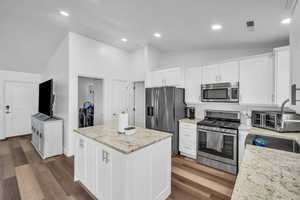 Kitchen with lofted ceiling, washing machine and dryer, appliances with stainless steel finishes, and dark wood-style flooring