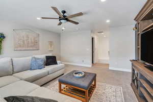 Living area with light carpet, a textured ceiling, recessed lighting, and baseboards