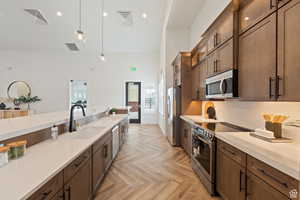 Kitchen with hanging light fixtures, visible vents, appliances with stainless steel finishes, and a sink