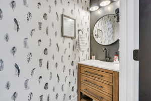 Bathroom featuring wallpapered walls and vanity