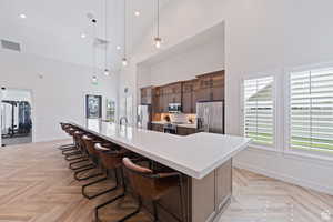 Kitchen with light countertops, high vaulted ceiling, visible vents, and stainless steel appliances