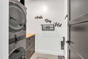 Laundry room featuring baseboards and stacked washer / drying machine