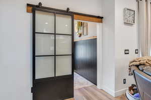 Interior space with a barn door, wood finished floors, and baseboards