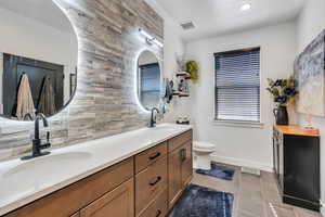 Bathroom featuring backsplash, a sink, visible vents, and tile patterned floors