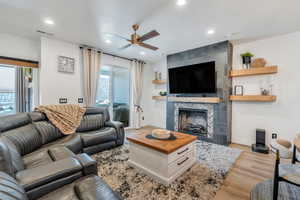 Living room featuring baseboards, visible vents, a tile fireplace, wood finished floors, and recessed lighting