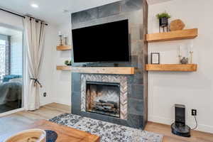 Living area with a tile fireplace, baseboards, and wood finished floors