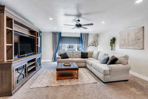 Living room with baseboards, a ceiling fan, carpet, a textured ceiling, and recessed lighting