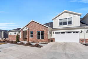 View of front of property featuring board and batten siding, brick siding, driveway, and an attached garage