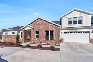 View of front facade featuring an attached garage, brick siding, board and batten siding, and concrete driveway