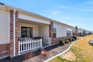 View of side of home featuring brick siding, fence, a lawn, and central AC unit