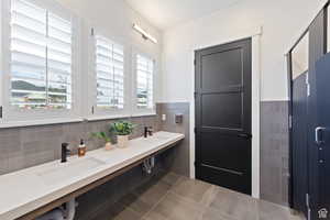 Bathroom with tile patterned flooring, tile walls, a wainscoted wall, and a sink