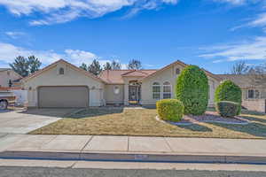 View of front of home featuring a tile roof, stucco siding, concrete driveway, a garage, and a front lawn