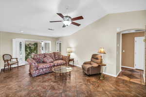 Living room with baseboards, vaulted ceiling, visible vents, and arched walkways