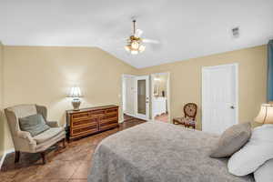 Bedroom with baseboards, visible vents, connected bathroom, a ceiling fan, and vaulted ceiling