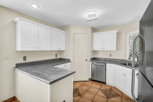 Kitchen featuring dark countertops, visible vents, appliances with stainless steel finishes, and white cabinets