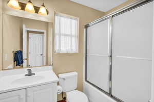 Full bath with toilet, shower / bath combination with glass door, and vanity