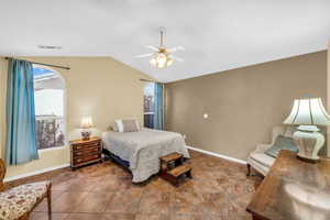 Bedroom featuring vaulted ceiling, a ceiling fan, visible vents, and baseboards