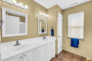 Bathroom featuring double vanity, visible vents, a sink, and tile patterned floors